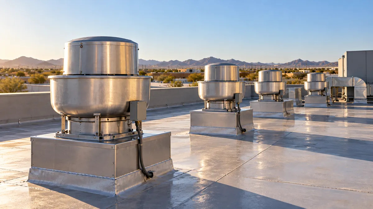 Wide daytime view of a flat commercial roof with a row of clean kitchen exhaust fans and wiped duct curbs, the roofing free of grease stains
