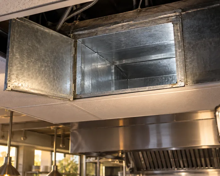 Open access panel on a grease duct showing clean metal inside